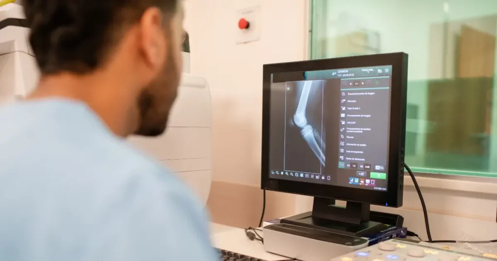 medical professional viewing an X-ray of a knee on a health information system laptop.|medical professional viewing an X-ray of a knee on a health information system laptop.